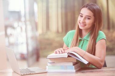 Dizüstü bilgisayar ve akıllı telefon kullanan genç kadın. Dizüstü bilgisayarda çalışma ve eğitim güzel öğrenci kız