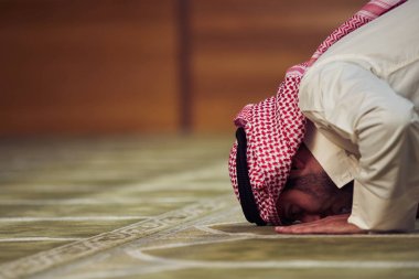 Dindar Müslüman adam caminin içinde dua ediyor.