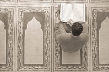 Dindar Müslüman adam caminin içinde dua ediyor.