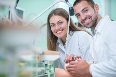 Takma diş, ağız hijyeni. Takma diş, takma diş, bir çalışma ve diş araçları içeren bir tablo üzerinde çalışırken protez eller.