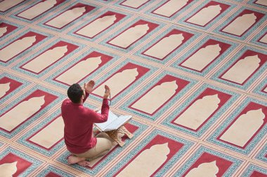 Dindar Müslüman adam caminin içinde dua ediyor.