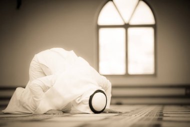 Dindar Müslüman adam caminin içinde dua ediyor.