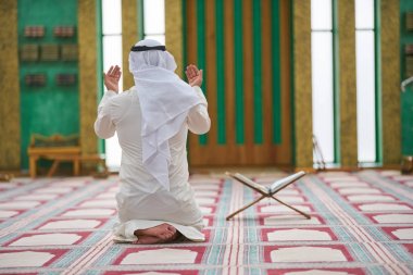Dindar Müslüman adam caminin içinde dua ediyor.