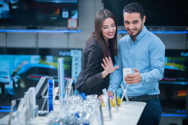 tüketici elektroniği genç bir çift satın almak en son dizüstü bilgisayar, televizyon ve fotoğraf kamera seyir saklamak