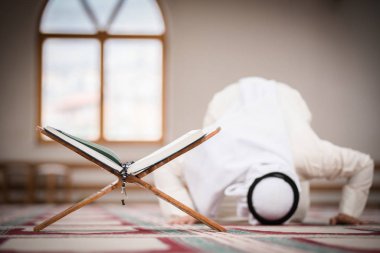 Dindar Müslüman adam caminin içinde dua ediyor.