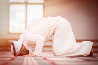 Dindar Müslüman adam caminin içinde dua ediyor.