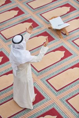 Dindar Müslüman adam caminin içinde dua ediyor.