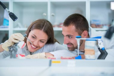 Takma diş, ağız hijyeni. Takma diş, takma diş, bir çalışma ve diş araçları içeren bir tablo üzerinde çalışırken protez eller.