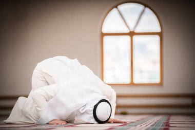 Dindar Müslüman adam caminin içinde dua ediyor.