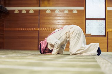 Dindar Müslüman adam caminin içinde dua ediyor.