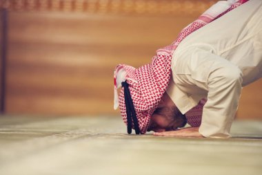 Dindar Müslüman adam caminin içinde dua ediyor.