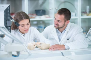 Takma diş, ağız hijyeni. Takma diş, takma diş, bir çalışma ve diş araçları içeren bir tablo üzerinde çalışırken protez eller.