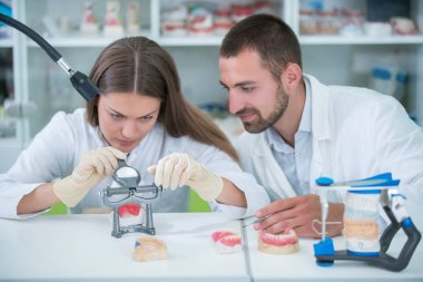 Takma diş, ağız hijyeni. Takma diş, takma diş, bir çalışma ve diş araçları içeren bir tablo üzerinde çalışırken protez eller.