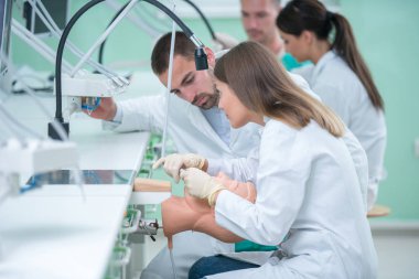 Takma diş, ağız hijyeni. Takma diş, takma diş, bir çalışma ve diş araçları içeren bir tablo üzerinde çalışırken protez eller.