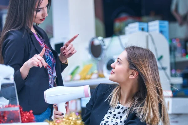 Saç bakım. Güzel uzun saçlı kadın elektronik mağazasında saç kurutma