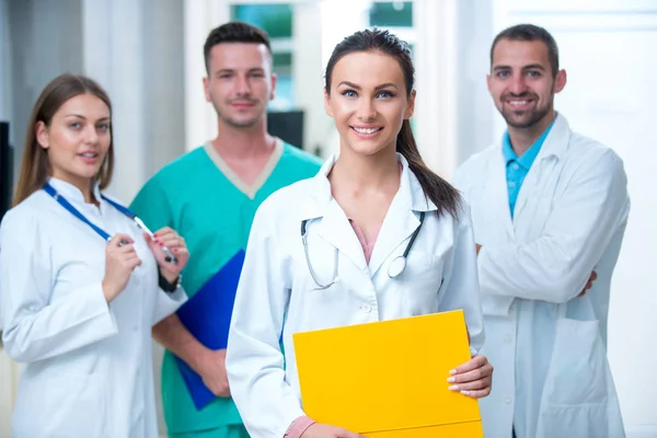 clinic, profession, people, health care and medicine concept - happy group of medics or doctors at hospital corridor