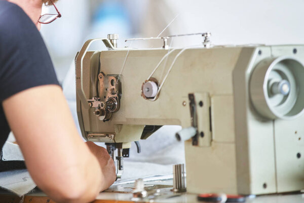 Seamstress or worker in a factory sewing with a industrial sewing machine