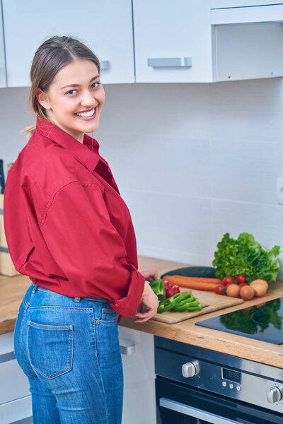 Closeup of a young woman cutting some fruit and vegetables to make herself a healthy juice at home