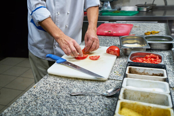 Chef sprinkling spices on dish in commercial kitchen