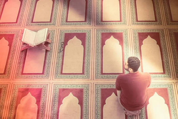 Dindar Müslüman adam caminin içinde dua ediyor.