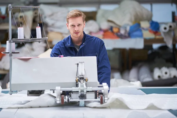 worker in protective clothing in factory using machine