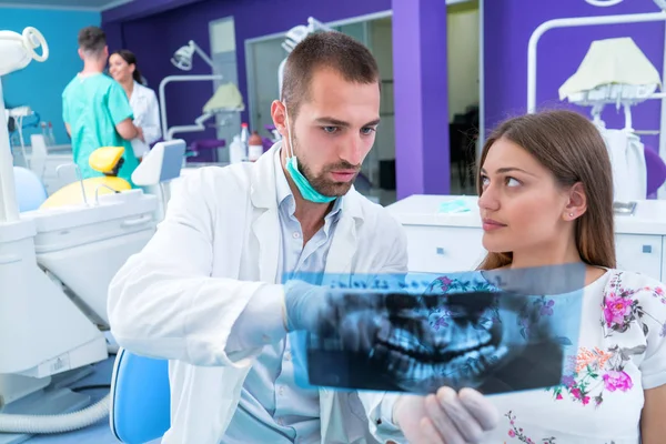 Dentist shows a patient x-ray of teeth in modern office
