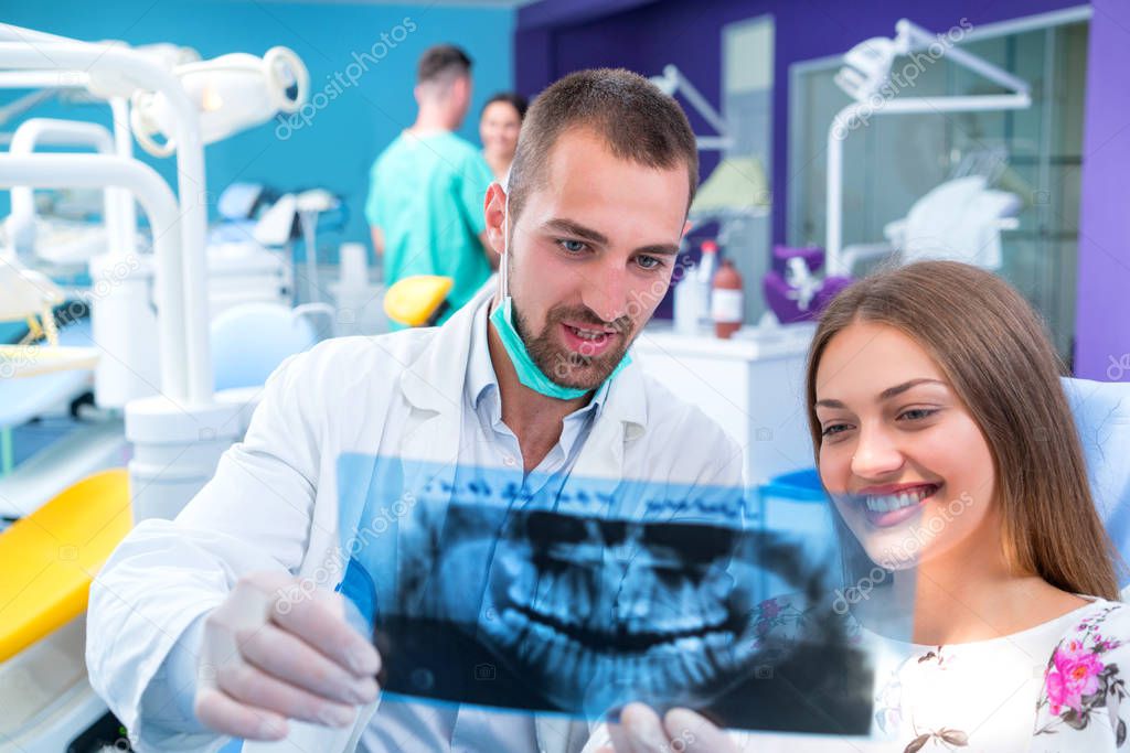 Dentist shows a patient x-ray of teeth in modern office