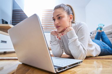 yerde yatarken ve dizüstü kullanan kadın