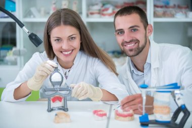 Takma diş, ağız hijyeni. Takma diş, takma diş, bir çalışma ve diş araçları içeren bir tablo üzerinde çalışırken protez eller.