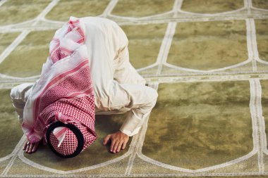 Dindar Müslüman adam caminin içinde dua ediyor.