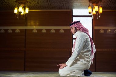 Dindar Müslüman adam caminin içinde dua ediyor.