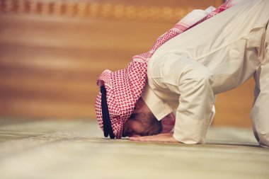 Dindar Müslüman adam caminin içinde dua ediyor.