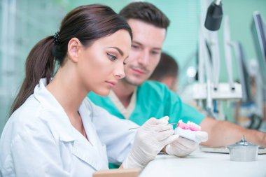 Takma diş, ağız hijyeni. Takma diş, takma diş, bir çalışma ve diş araçları içeren bir tablo üzerinde çalışırken protez eller.