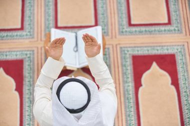 Dindar Müslüman adam caminin içinde dua ediyor.