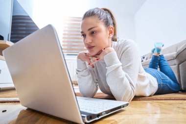 yerde yatarken ve dizüstü kullanan kadın