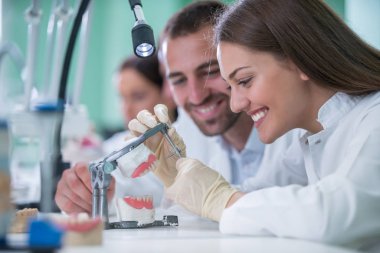 Takma diş, ağız hijyeni. Takma diş, takma diş, bir çalışma ve diş araçları içeren bir tablo üzerinde çalışırken protez eller.