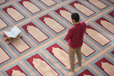 Dindar Müslüman adam caminin içinde dua ediyor.