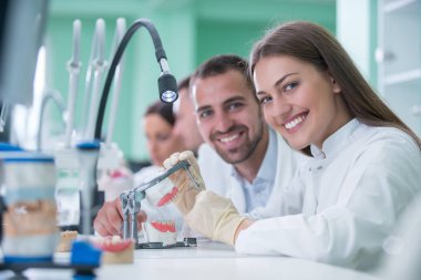 Takma diş, ağız hijyeni. Takma diş, takma diş, bir çalışma ve diş araçları içeren bir tablo üzerinde çalışırken protez eller.