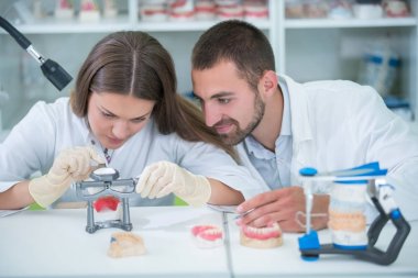 Takma diş, ağız hijyeni. Takma diş, takma diş, bir çalışma ve diş araçları içeren bir tablo üzerinde çalışırken protez eller.