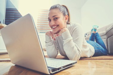 yerde yatarken ve dizüstü kullanan kadın