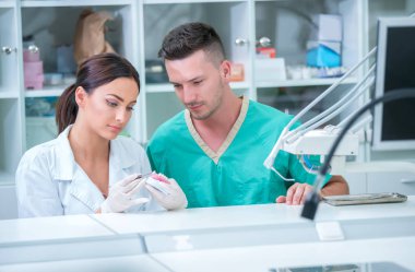 Takma diş, ağız hijyeni. Takma diş, takma diş, bir çalışma ve diş araçları içeren bir tablo üzerinde çalışırken protez eller.