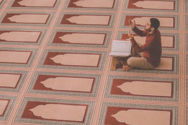 Dindar Müslüman adam caminin içinde dua ediyor.