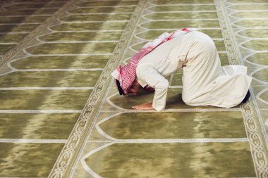Dindar Müslüman adam caminin içinde dua ediyor.