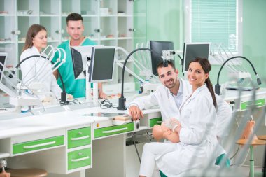 Takma diş, ağız hijyeni. Takma diş, takma diş, bir çalışma ve diş araçları içeren bir tablo üzerinde çalışırken protez eller.