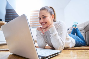 yerde yatarken ve dizüstü kullanan kadın