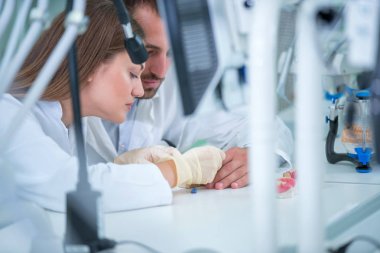 Takma diş, ağız hijyeni. Takma diş, takma diş, bir çalışma ve diş araçları içeren bir tablo üzerinde çalışırken protez eller.