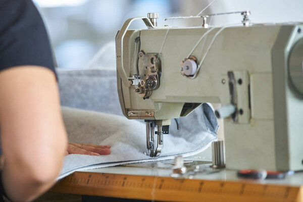 Seamstress or worker in a factory sewing with a industrial sewing machine, she is very accurate