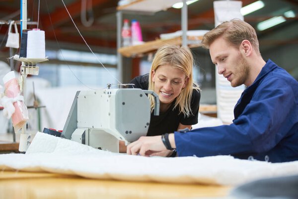 Seamstress is new assigned to a machine in a textile factory, the foreman explains something