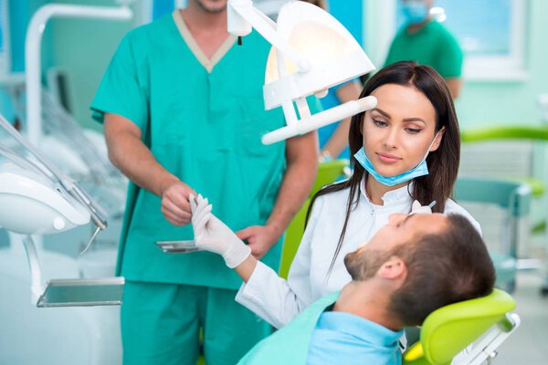 Дантист осматривает зубы пациента у стоматолога
.