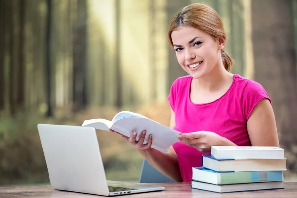 Young woman using laptop computer and smart phone. Beautiful student girl working on laptop and studying